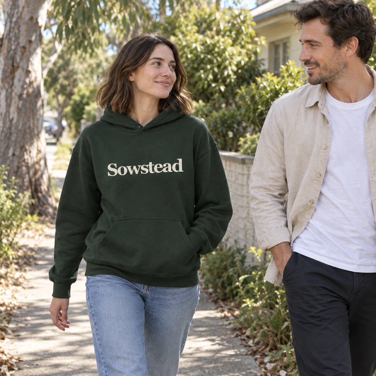 A woman wearing the Forest Green Sowstead Core Hoodie while walking with a friend, front view.