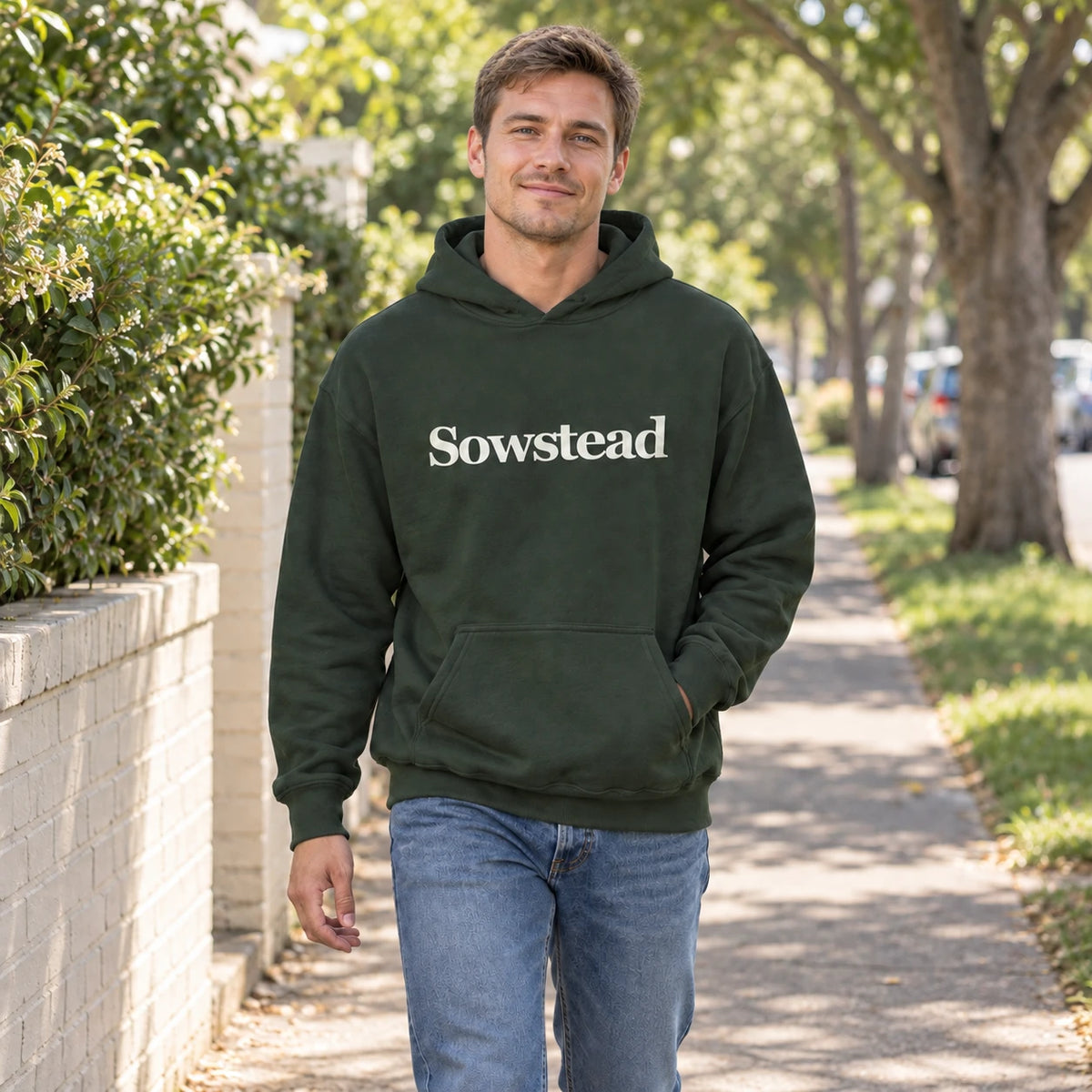 A man wearing the Forest Green Sowstead Core Hoodie, with the cream chest wordmark clearly visible.