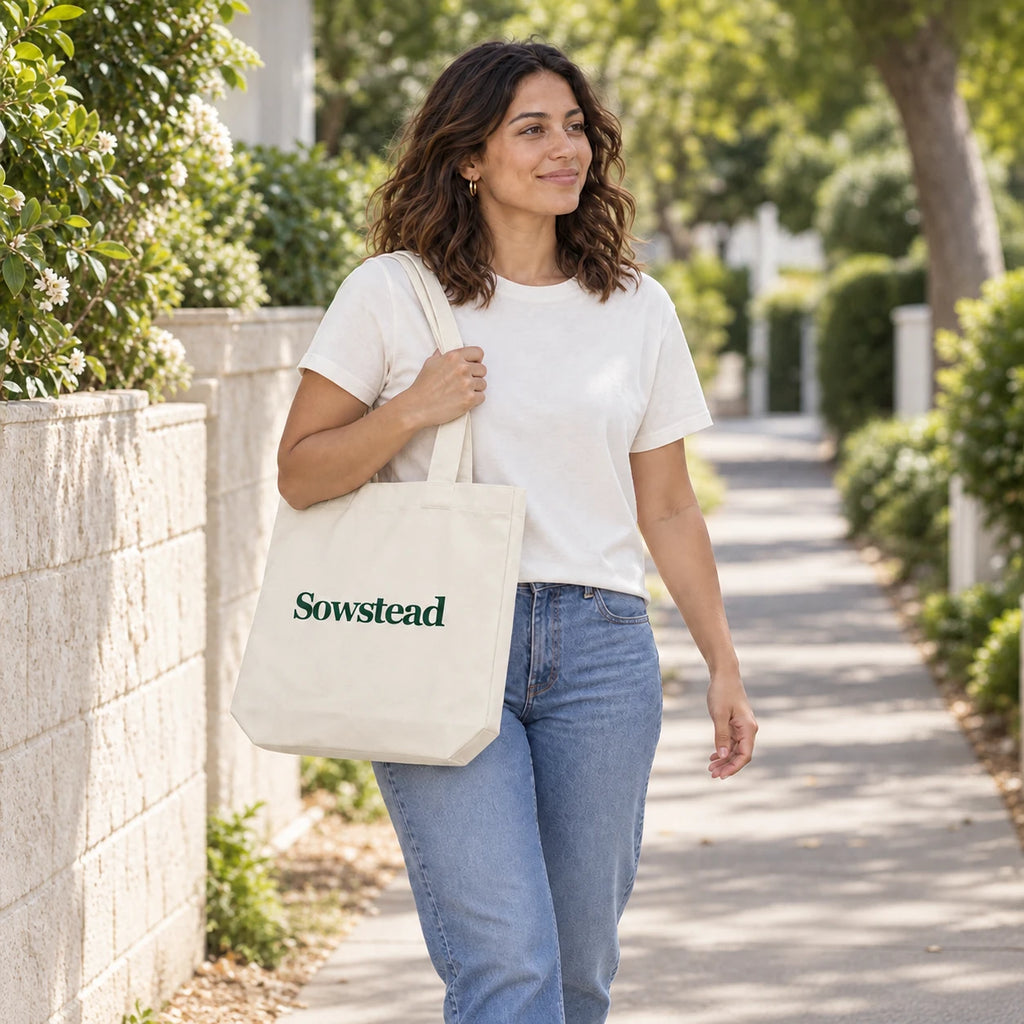 A woman carrying the natural Sowstead tote over her shoulder on a leafy neighbourhood footpath.