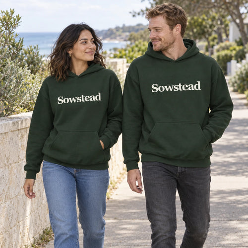 A woman and man walking together in Forest Green Sowstead Core Hoodies, showing both cream front wordmarks.
